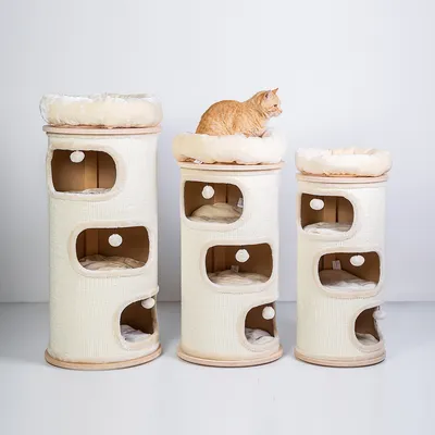 Drei beige Kratzbaumtürme mit mehreren Ebenen, Höhlen und Spielbällen. Eine orangefarbene Katze sitzt auf dem mittleren Turm oben auf einem gepolsterten Liegeplatz.