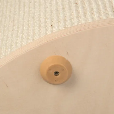 Nærbillede af samling med beige plastskrue i lyst træ og synlig overflade af hvidt sisalstof. Viser materialer og konstruktion.