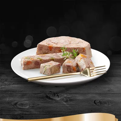 Kostky masové směsi s viditelnými kousky zeleniny na bílém talíři, zlatá vidlička a snítka bylinky vedle. Produkt prezentován pro komerční účely.