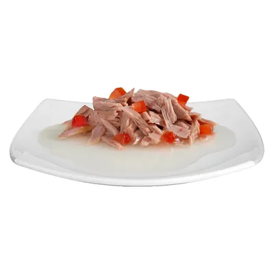 Primo piano di tonno sminuzzato con pezzi di peperone rosso su piatto bianco, servito in salsa chiara.