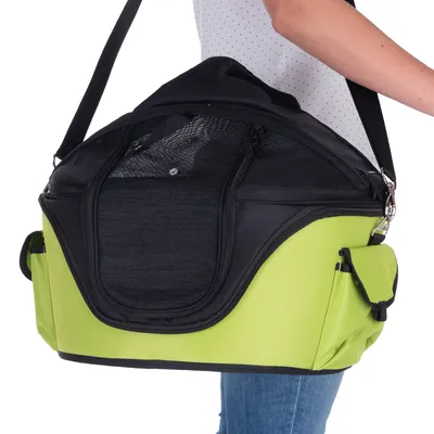 Sac de transport vert et noir avec bandoulière, poches latérales et ouverture en maille, porté à l’épaule par une personne en jean et haut blanc à pois.