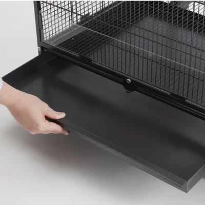 Hand zieht eine herausnehmbare schwarze Schublade unter einem Metallkäfig hervor, geeignet zur einfachen Reinigung.