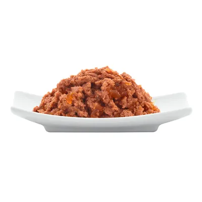 Aprított, barna színű nedves állateledel fehér tálon, csomagolás vagy márkajelzés nélkül látható.