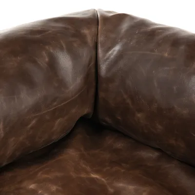 Detailný záber na hnedé kožené kreslo so zreteľnou štruktúrou a záhybmi na materiáli.
