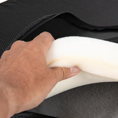 Hand zeigt herausnehmbaren Schaumstoffkern aus einer schwarzen, wasserabweisenden Hülle mit Reissverschluss.