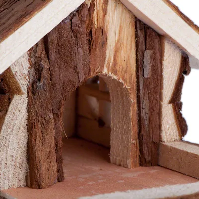 Entrée d’une maisonnette pour petits animaux en bois brut, avec façade et toit visibles, matériaux naturels apparents.