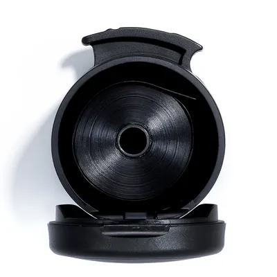 Dispenser in plastica nero visto dall'alto, con coperchio aperto e rotolo di sacchetti visibile all'interno.