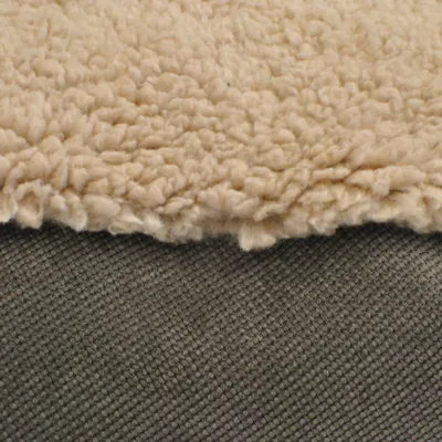 Detailansicht von zwei Materialien: oben cremefarbenes, flauschiges Textil, unten grauer, strukturierter Stoff.