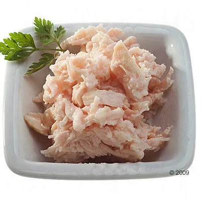 Wit keramisch bakje met stukjes lichtroze vlees, gegarneerd met een takje peterselie. Geen merknaam of tekst zichtbaar.