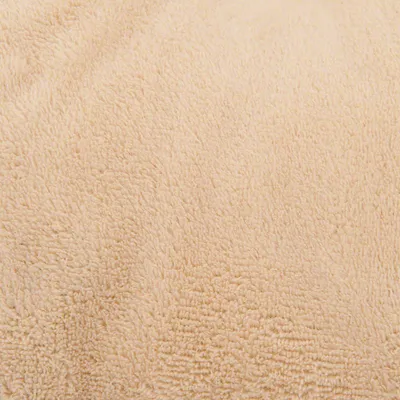 Nærbillede af beige tekstil med tydelig blød, fleecelignende struktur. Materialet fremstår som stof uden synlige mærker eller tekst.