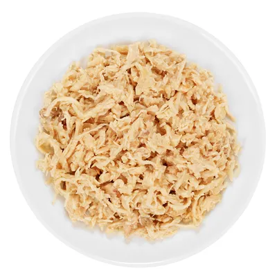 Schale mit fein zerkleinertem, hellbraunem Fleisch auf weißem Teller, Nahaufnahme des Produkts.