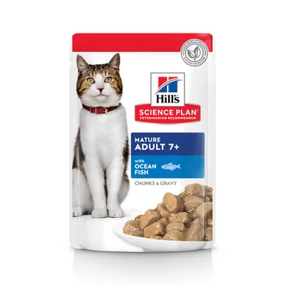 Hill's Science Plan Mature Adult 7+ with Ocean Fish, trozos en salsa. Imagen de un gato y comida húmeda en plato. Sin conservantes ni colorantes artificiales visibles en el envase.