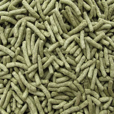 Close-up of greenish-brown compressed food pellets, shown in bulk. No visible brand or packaging.
