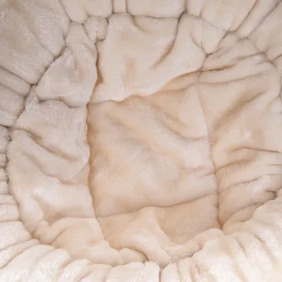 Close-up of beige, soft plush material with padded seams, suitable for cosy surfaces or upholstery.