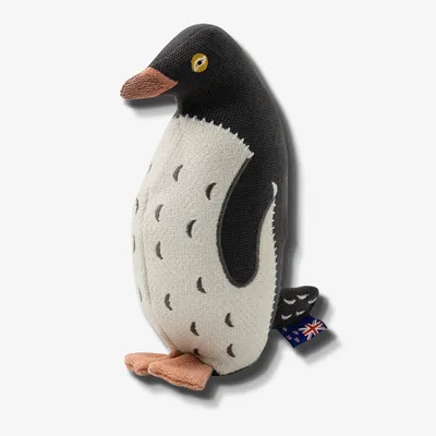 Stuffed penguin-shaped pet toy with stitched details and a small fabric tag showing the Australian flag attached to its side.