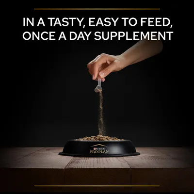 PURINA PRO PLAN tál eledellel, kéz por állagú kiegészítőt szór rá. Felirat: IN A TASTY, EASY TO FEED, ONCE A DAY SUPPLEMENT (angol nyelvű).