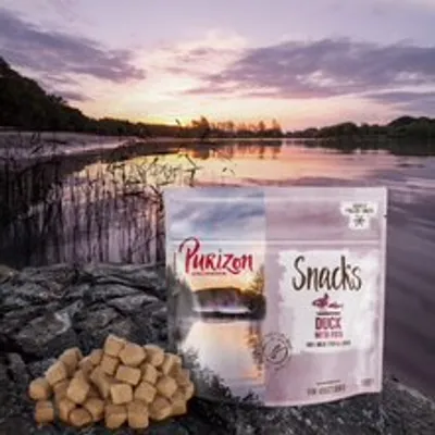 Purizon snackek kacsával és hallal. Gabonamentes, magas hústartalom. Csomagolás snackkockák mellett, tó előtt naplementében.