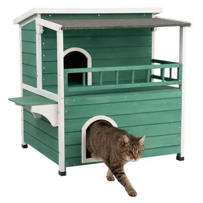 Casa para gatos de madera verde con dos niveles, balcón y entrada cubierta. Un gato sale por la abertura inferior.