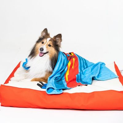 Niebieski koc z motywem Superman, czerwonym peleryną i żółtym symbolem na piersi. Wzór z czerwonymi i niebieskimi geometrycznymi kształtami.