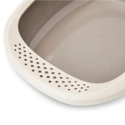 Plastičen rob mačjega stranišča z okroglimi prezračevalnimi luknjami, vidna notranjost v svetlo sivi barvi.
