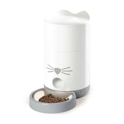 Weisser Futterautomat mit Katzengesicht-Design und grauer Futterschale, gefüllt mit Trockenfutter.