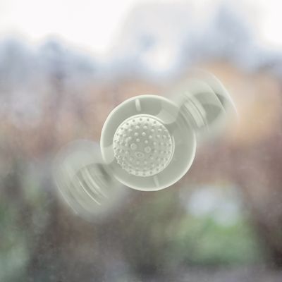 Λευκό παιχνίδι με βεντούζες και μπάλα με εξογκώματα, στερεωμένο σε γυάλινη επιφάνεια.