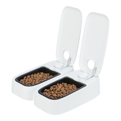 Distributore automatico doppio per crocchette, due vaschette nere con coperchi bianchi aperti, ciascuna riempita con crocchette marroni.