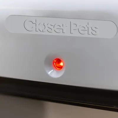 Closer Pets, voyant lumineux rouge allumé sur un appareil en plastique blanc Closer Pets, voyant lumineux rouge allumé sur un appareil en plastique blanc