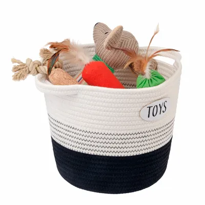 Spielzeugkorb aus Stoff mit der Aufschrift 'Toys', gefüllt mit verschiedenen Haustierspielzeugen wie Seil, Karotte und Maus.