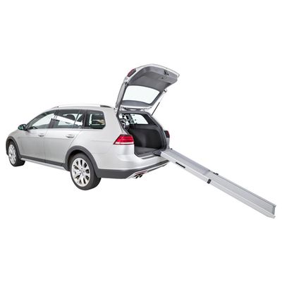 Srebrny samochód kombi z otwartym bagażnikiem i rozłożoną metalową rampą prowadzącą do wnętrza bagażnika.