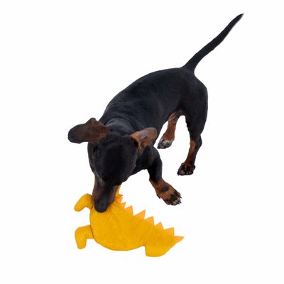 Куче играе с жълка плюшена играчка във формата на крокодил.