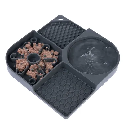 Grått foderbricka med fyra sektioner: vatten, strukturerade ytor och en sektion för våtfoder. Synlig design för långsam utfodring.