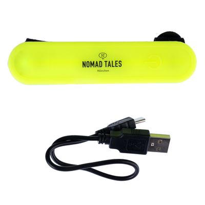 Nomad Tales München opaska LED w kolorze żółtym z kablem USB do ładowania. Widoczny symbol włączania/wyłączania na opasce.