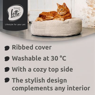 Letto per animali rotondo, grigio chiaro con imbottitura bianca e struttura a righe. Etichetta in pelle con la scritta 'Designed by Lotte' visibile.
