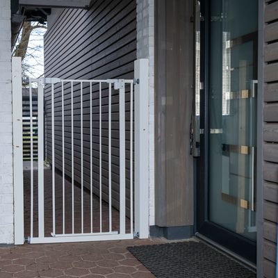Bílé kovové ochranné dveře, namontované mezi dvěma stěnami, vhodné pro vstupy nebo průchody.