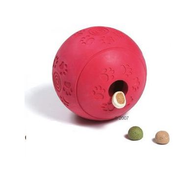 Rød bold af gummi med poteaftryk, hul i siden og godbidder synlige ved åbningen samt to godbidder ved siden af bolden.