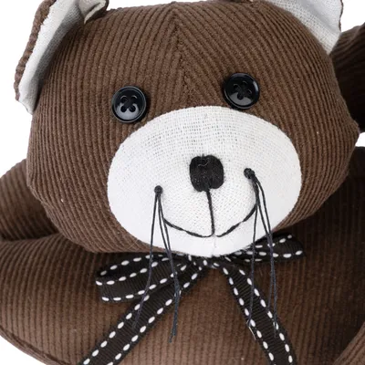 Peluche marrone a forma di orso con occhi a bottone, viso bianco e fiocco nero a pois bianchi.