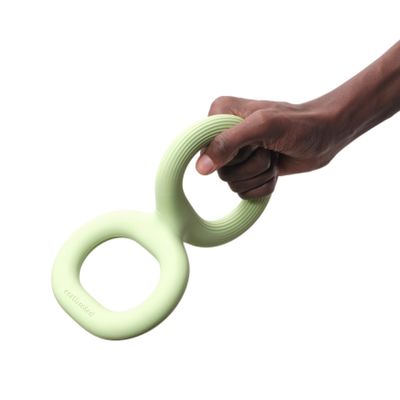 Mano che tiene un gioco verde chiaro con due manici ovali, marchio 'cattitude' visibile sul prodotto.