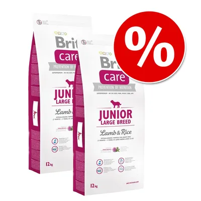 Două saci Brit Care Junior Large Breed Lamb & Rice, 12 kg fiecare, cu simbol procent roșu pentru promoție. Text vizibil: PREVENTION BY NUTRITION, hypoallergenic formula.