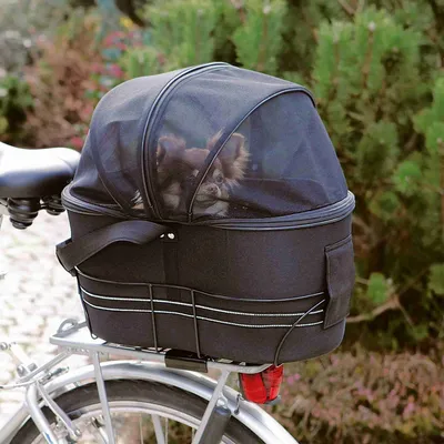 Cykelkorg med svart tyg och nätöverdrag, monterad på en pakethållare. Liten hund synlig genom nätöverdraget.