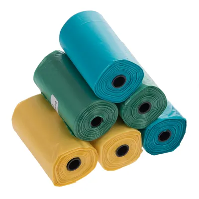 Cinq rouleaux de sacs en plastique, deux jaunes, deux verts et un bleu, empilés les uns sur les autres. Aucun texte ou marque visible.