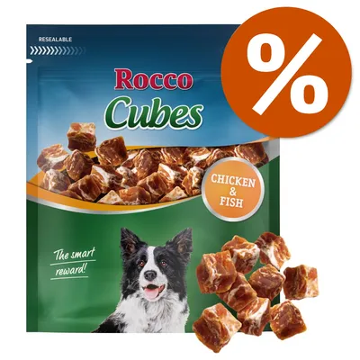 Rocco Cubes, snack per cani con pollo e pesce. Scritta visibile: CHICKEN & FISH. Immagine di cubetti e cane sulla confezione. Simbolo percentuale arancione in alto a destra.