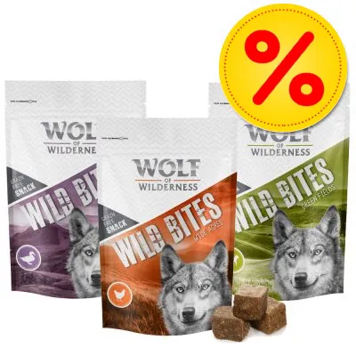 Tre påsar Wolf of Wilderness Wild Bites hundsnacks i olika smaker, synliga bitar framför förpackningarna. Gul rabattikon med procenttecken uppe till höger.