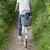 Cestino posteriore per bicicletta con griglia di sicurezza in metallo, contiene un cane di piccola taglia. Persona in jeans e maglietta guida la bici su un sentiero. Cestino posteriore per bicicletta con griglia di sicurezza in metallo, contiene un cane di piccola taglia. Persona in jeans e maglietta guida la bici su un sentiero.