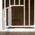 White metal safety gate with small opening, suitable for pet areas or safety zones. Gate mounted on wooden floor.