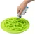 Hand applying paste to a green lick mat with wavy pattern.