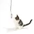 Chat tigré blanc et gris jouant avec une longue baguette à plumeau gris suspendue, accessoire pour chat visible en entier.