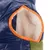 Nahaufnahme eines blauen Schlafsacks mit orangefarbenem Rand und weichem, weissem Innenfutter. Detailansicht der Öffnung.