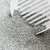 Close-up of grey cat litter being sifted with a white litter scoop.