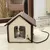 Heated cat house with brown roof and window, suitable for indoor use. Power cable visibly connected.
